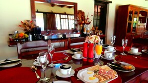 Un desayuno listo para dos personas, con una mesa dispuesta que incluye platos con huevos, tostadas, frijoles y tomates, además de tazas de café y jugo de naranja.