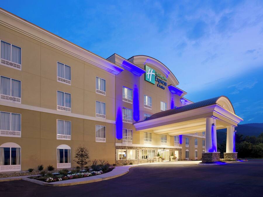 Un hotel Holiday Inn Express & Suites con un diseño moderno, que presenta una entrada destacada y una fachada bien iluminada.