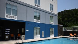 En modern byggnad med en swimmingpool, utomhusmöbler och ett takförsett område med stolar.