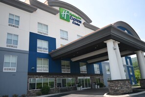 Un hotel Holiday Inn Express & Suites con una fachada moderna, ventanas grandes y una entrada cubierta.