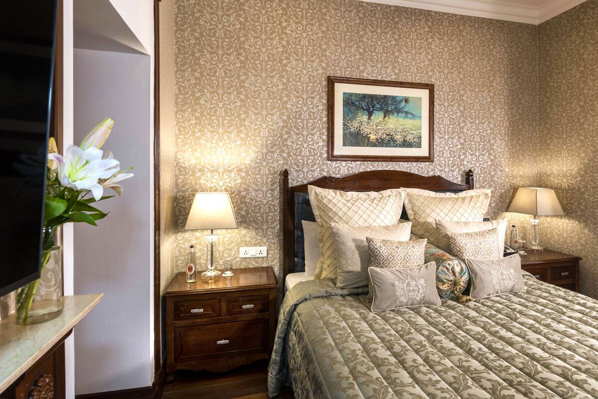 Un dormitorio ordenado con cama, dos mesitas de noche, televisor y un cuadro enmarcado en la pared.