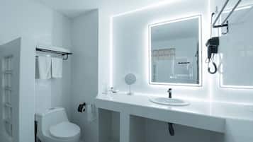 Un baño moderno con inodoro blanco, lavabo con espejo y un perchero para toallas.