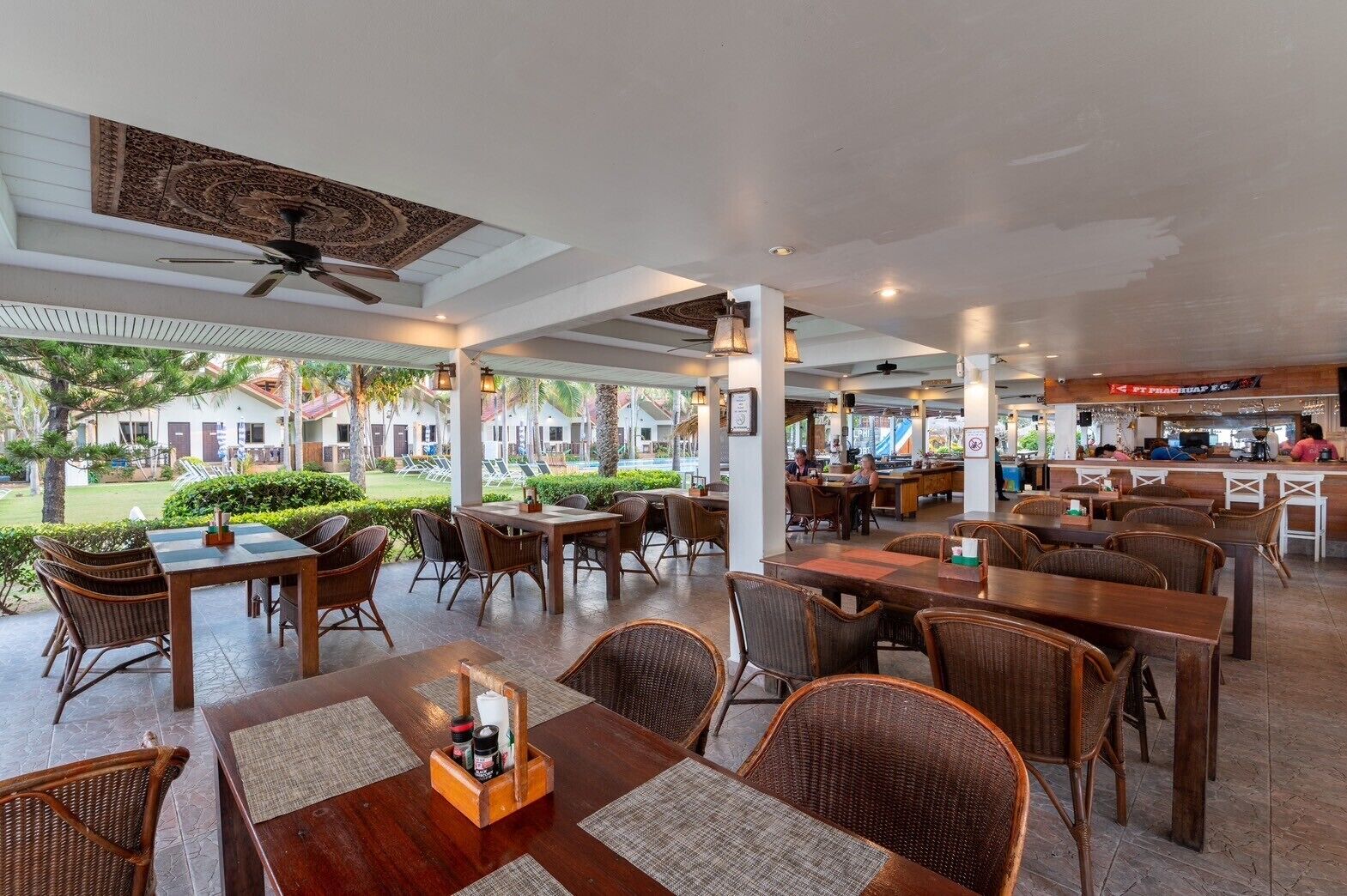 A spacious outdoor dining area with wicker furniture and a pool view.