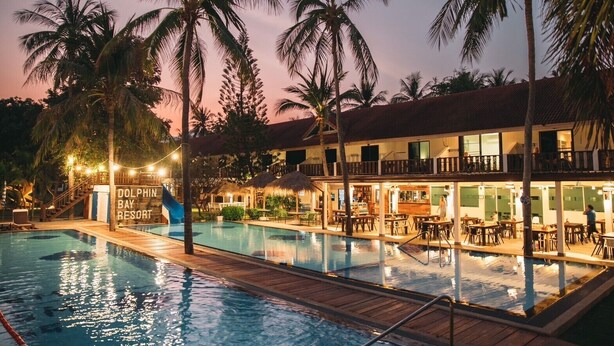 A resort with a swimming pool, outdoor seating, and a building with balconies. - Dolphin Bay Beach Resort (Sam Roi Yot)