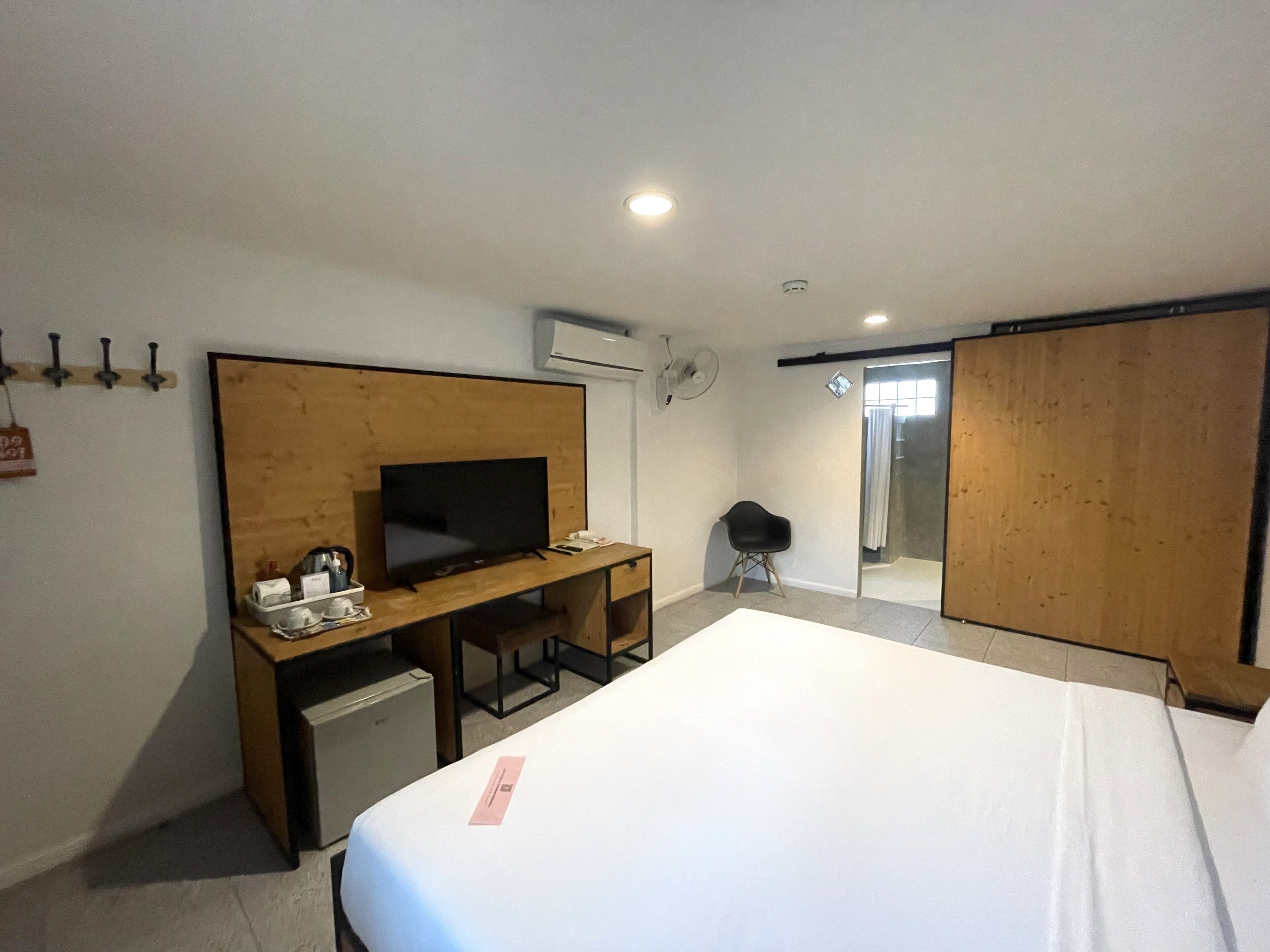 Ett hotellrum med en säng, ett skrivbord med en tv, en stol, ett litet bord och en garderob.