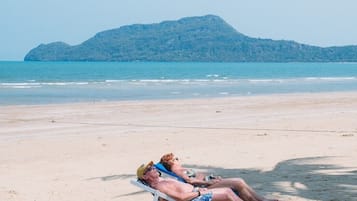 On the beach, white sand, sun loungers, beach umbrellas