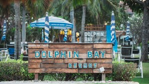 A wooden sign for Dolphin Bay Resort with a tropical background. - Dolphin Bay Beach Resort (Sam Roi Yot)