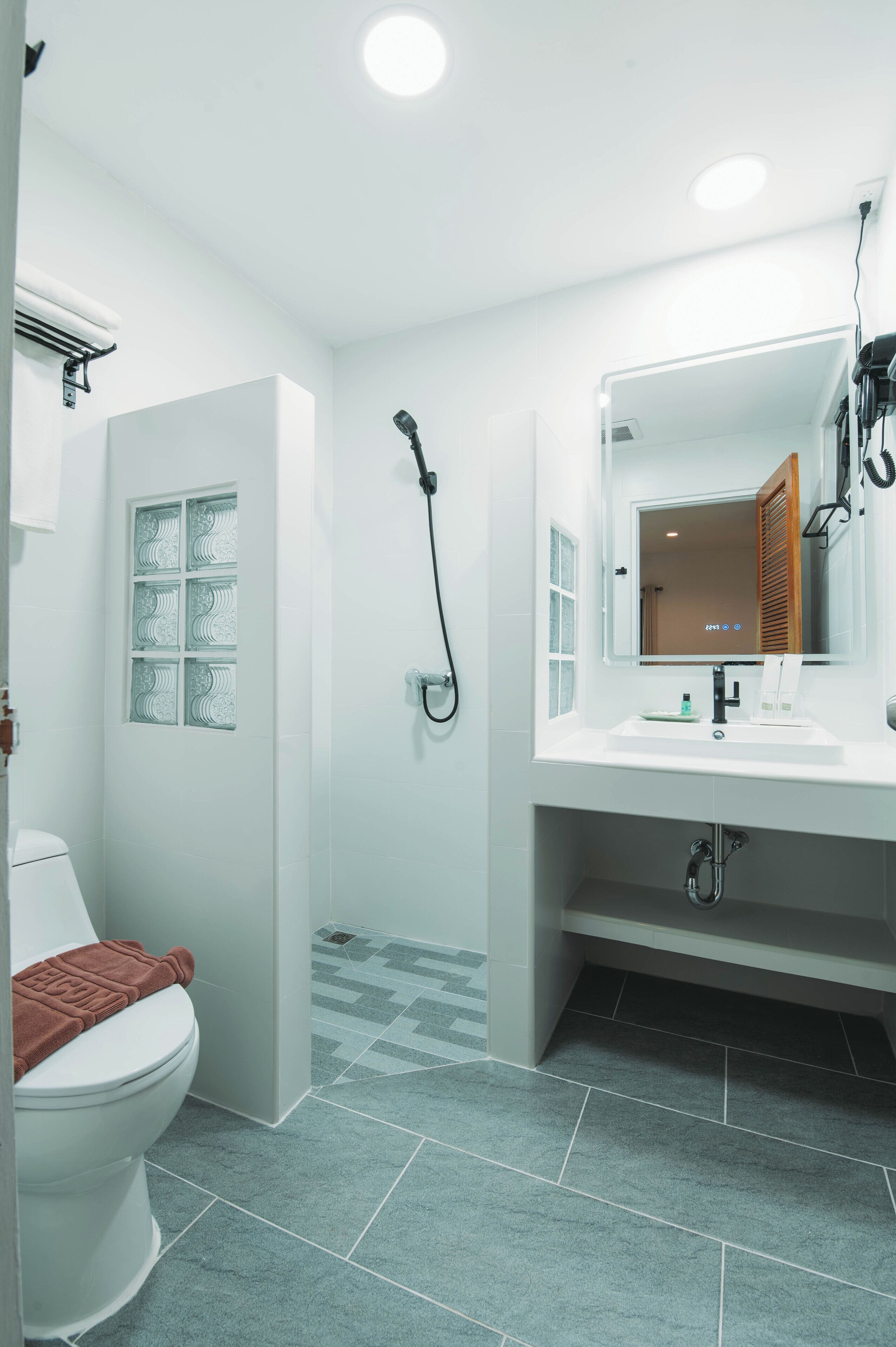 A modern bathroom with a white toilet, a shower, and a vanity with a mirror.