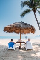Di pantai, pasir putih, kursi berjemur, dan payung pantai