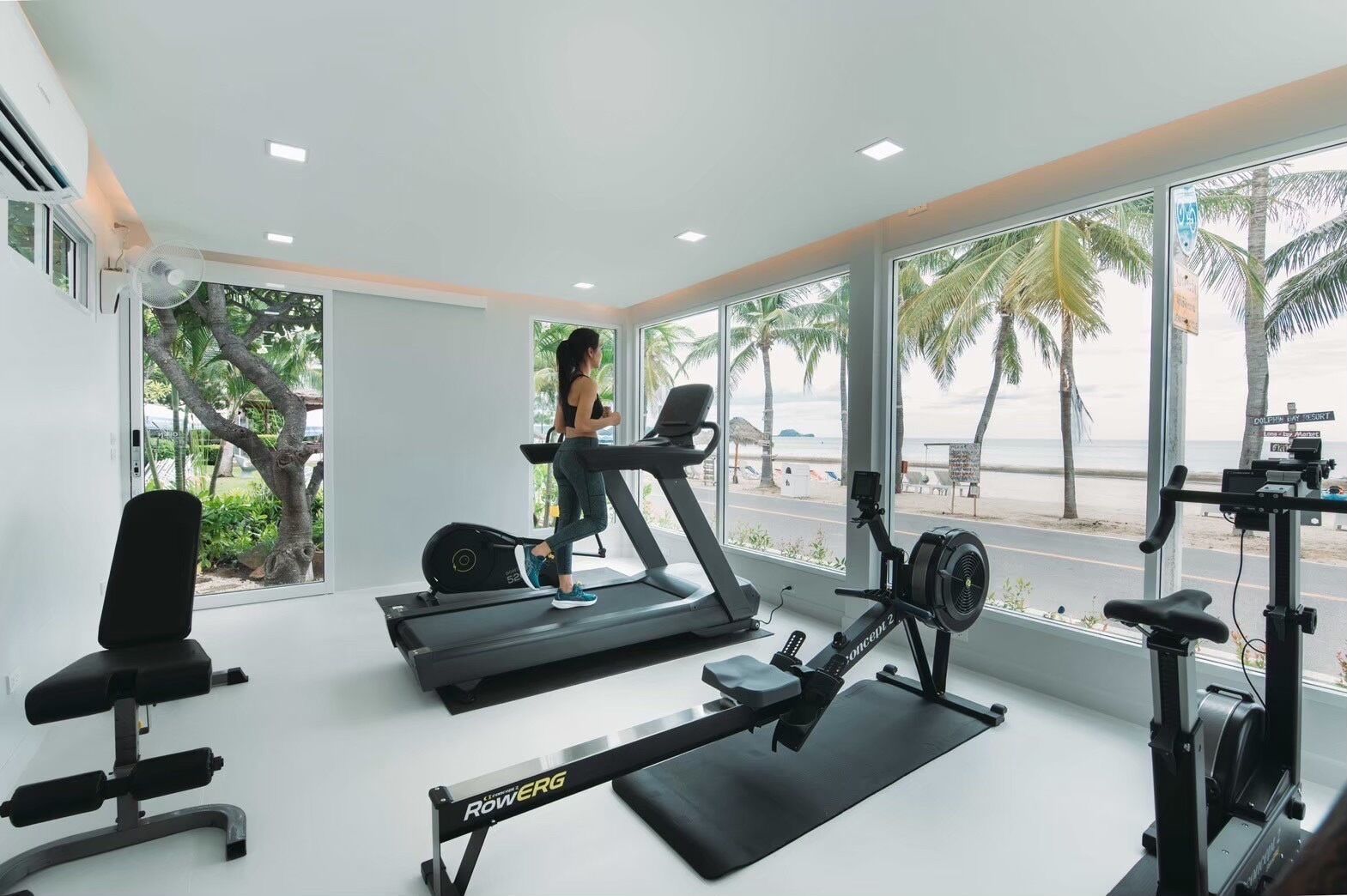 A gym with treadmills, a rowing machine, and a bench.