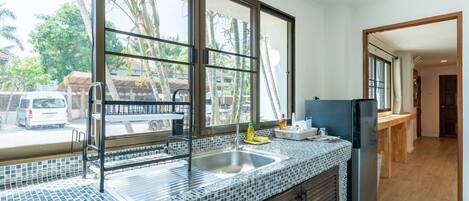 A kitchen with a large window, a sink, and a refrigerator.