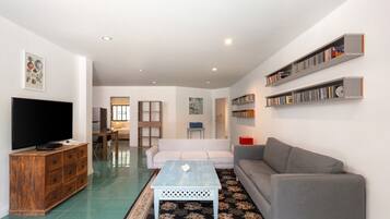 A living room with a TV, sofa, coffee table, and bookshelves.