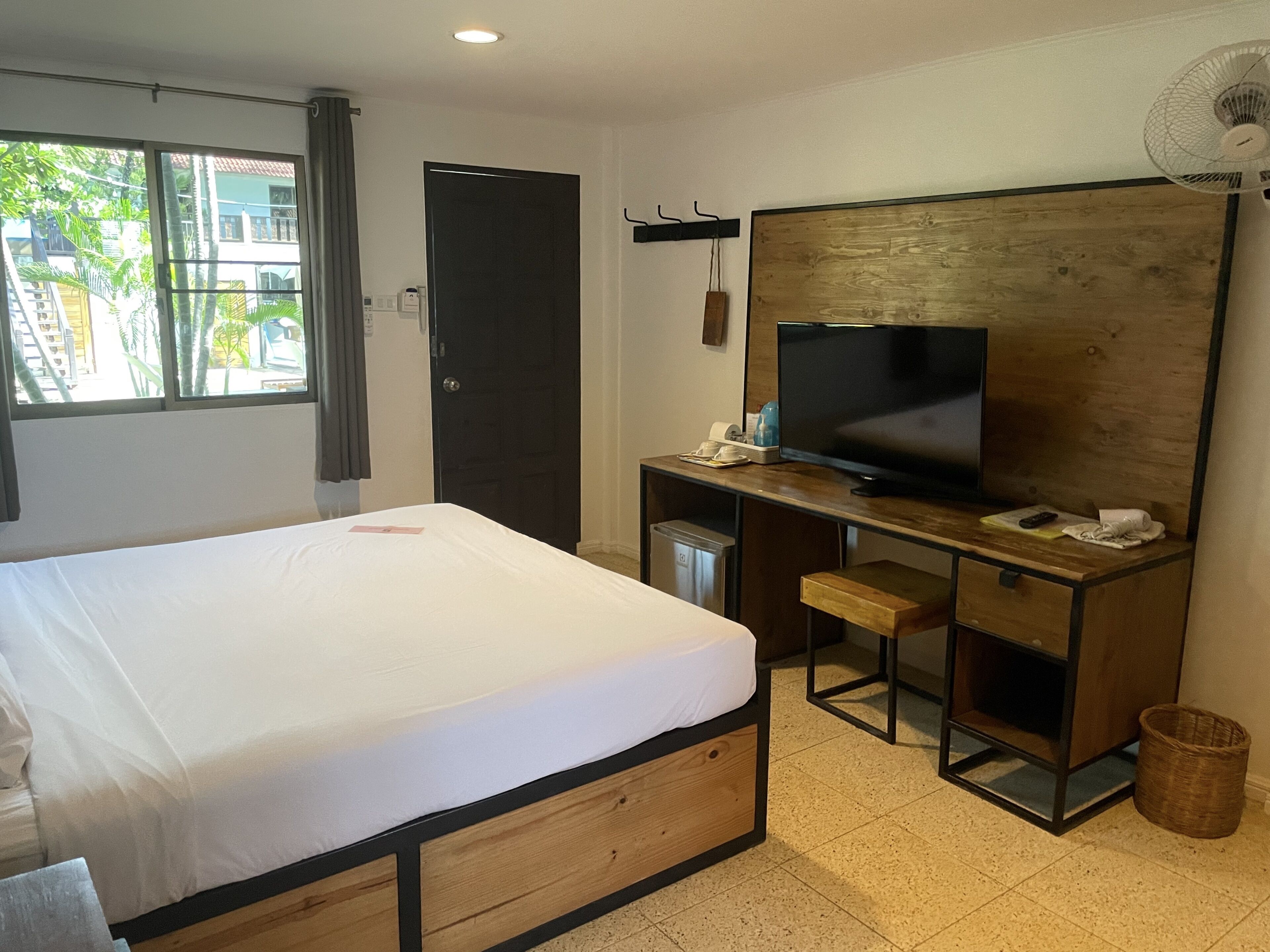 Ett hotellrum med en säng, ett skrivbord, en tv och utsikt över omgivningarna.