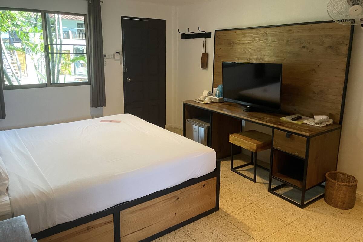 Ett hotellrum med en säng, ett skrivbord, en tv och utsikt över omgivningarna.