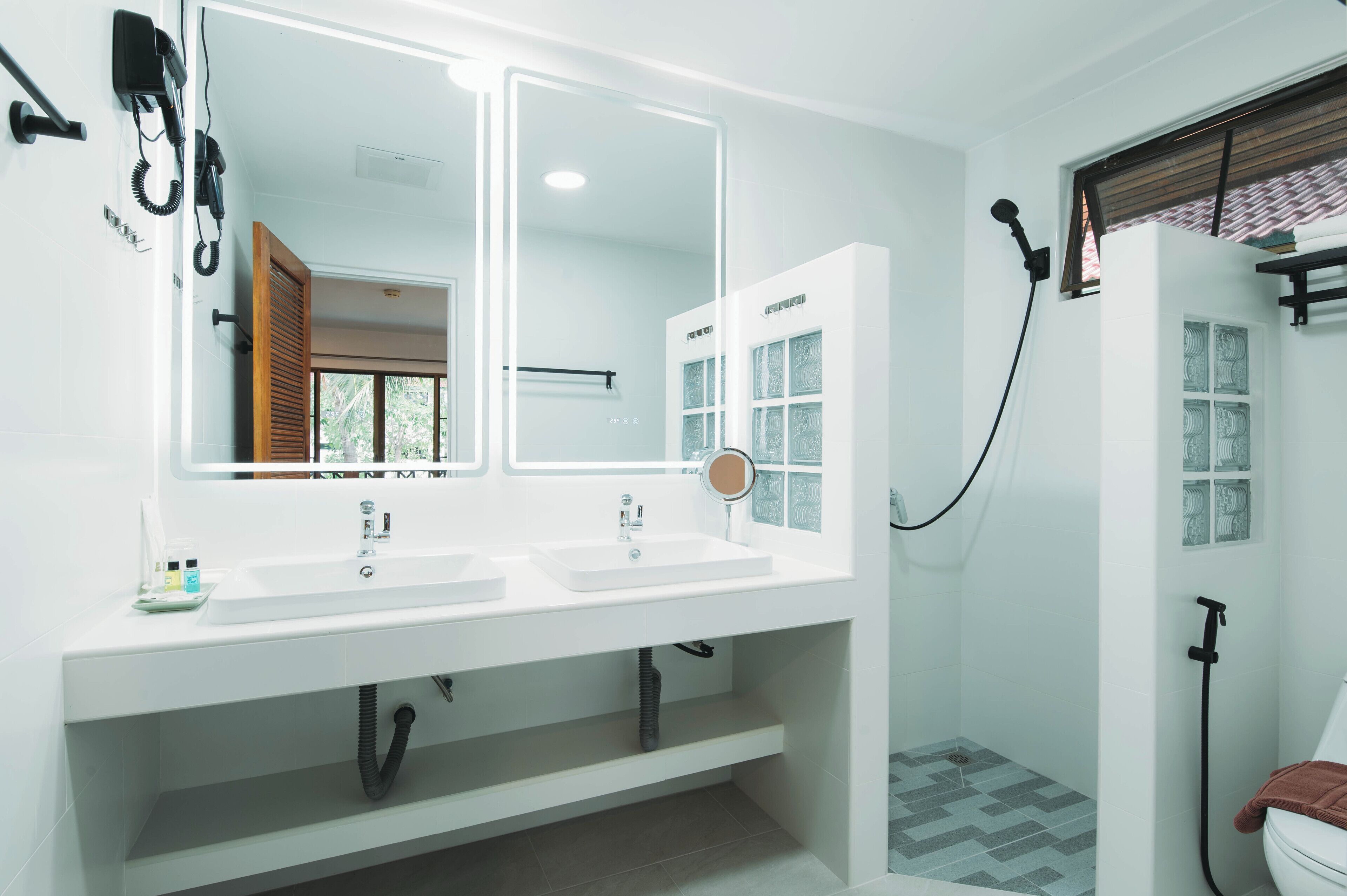 Un baño moderno con dos lavamanos, un espejo grande, ducha e inodoro.