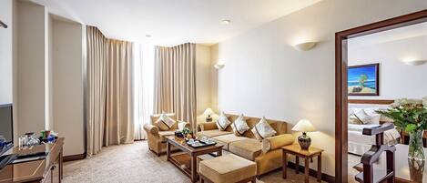 Une chambre d’hôtel comprenant un canapé, une table basse, un téléviseur et un bureau.