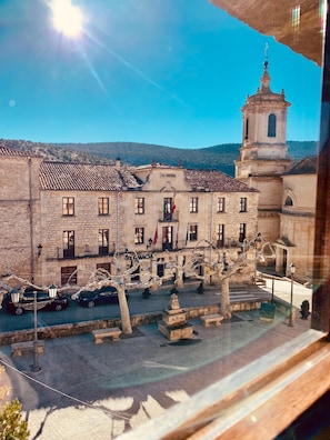 A historic building with a clock tower, stone facade, and a courtyard with benches and trees. - Hotel Tres Coronas de Silos (Santo Domingo de Silos)
