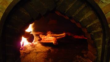 Un horno de ladrillo con fuego encendido en su interior, probablemente usado para cocinar o hornear.
