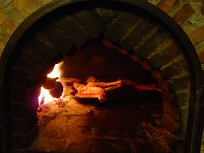 A brick oven with a fire burning inside, likely used for cooking or baking. - Hotel Tres Coronas de Silos (Santo Domingo de Silos)