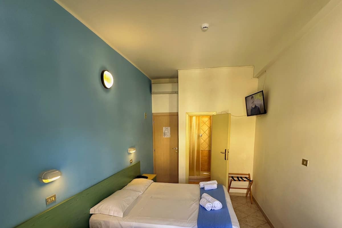A hotel room with two beds, a desk, a chair, a TV, and a bathroom door.