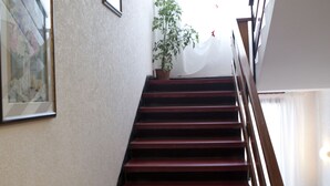 A staircase with wooden steps and a handrail, leading to a landing with a potted plant. - Hotel Sant'Angelo (Riccione)