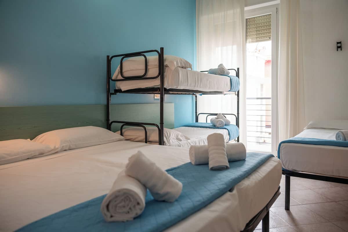 A hotel room with bunk beds, a single bed, and neatly folded towels on the beds.