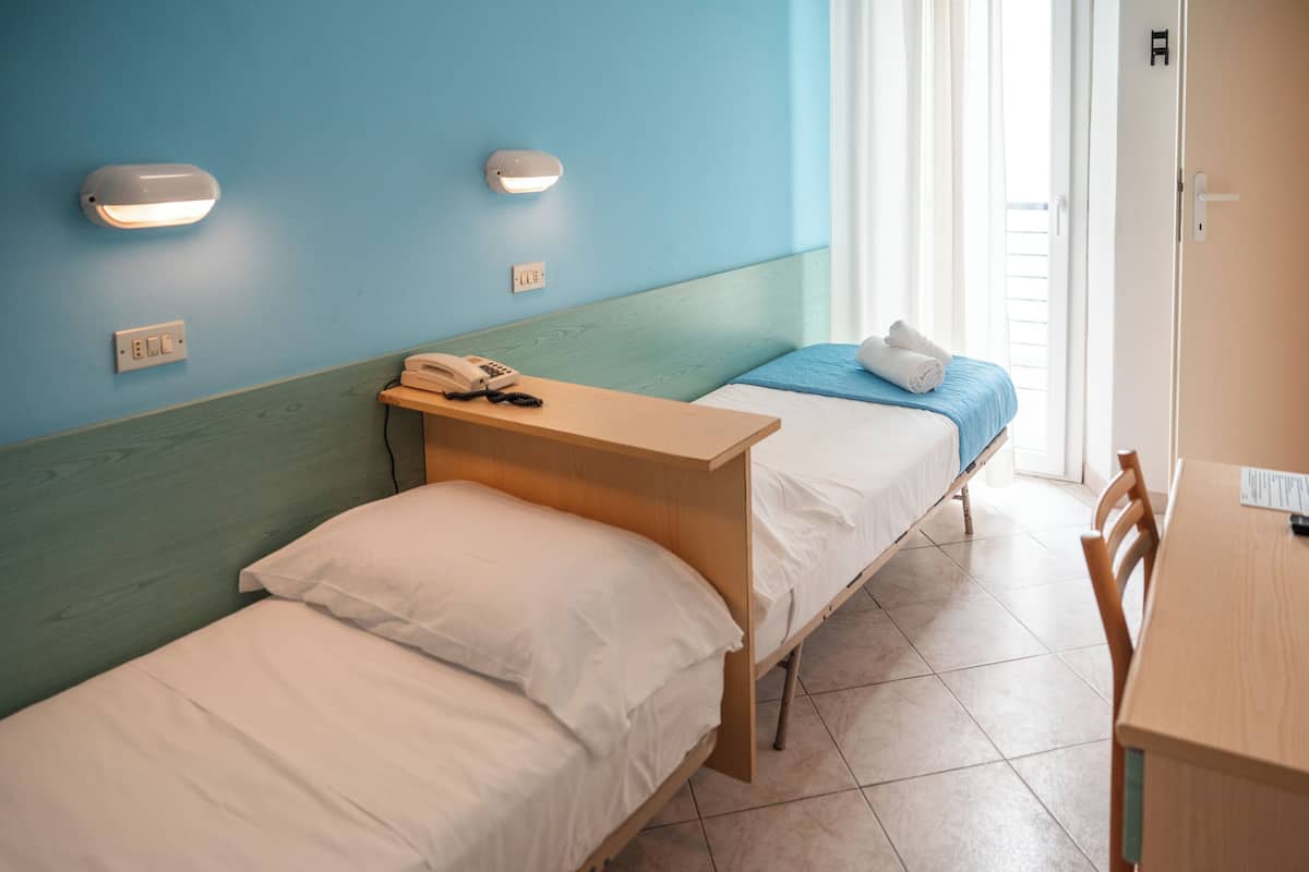 A room with two beds, a desk, and a chair.