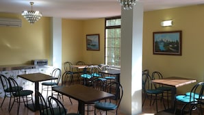 A dining area with multiple tables and chairs, a chandelier, and two paintings on the walls. - Hotel Azcona (Noja)