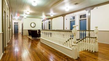 A hallway with wooden floors, white railings, and a staircase with a white balustrade.