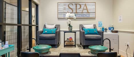 A spa room with two armchairs, a small table with a vase of flowers, and a sign that reads "SPA Florence".