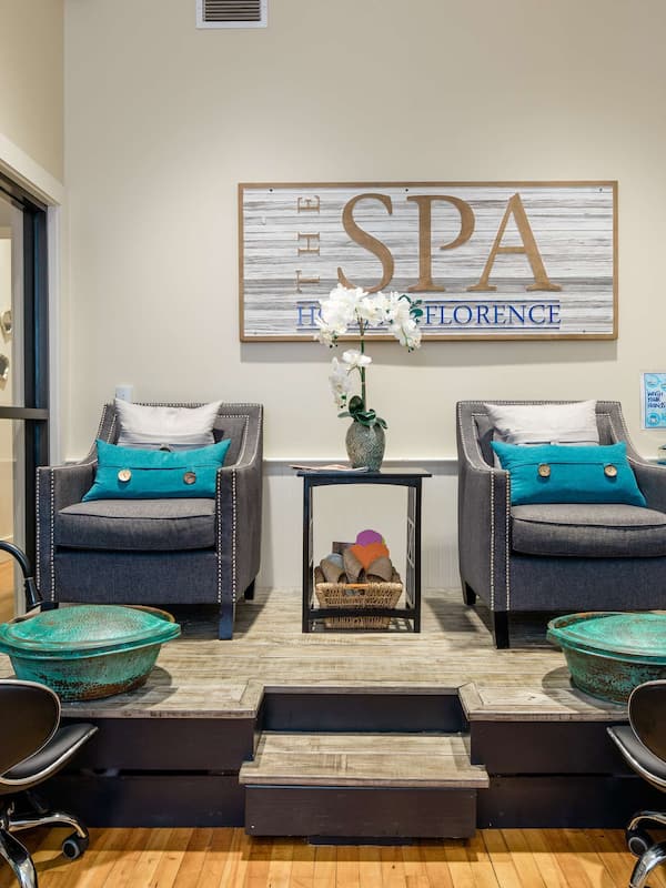 Relax in a serene spa room with comfortable seating, a decorative sign, and a self-service setup.