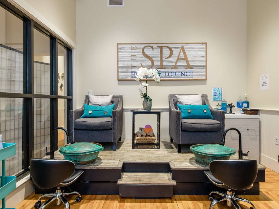 A spa room with two armchairs, a small table with a vase of flowers, and a sign that reads "SPA Florence".