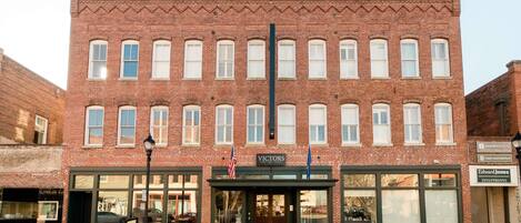 A brick building with storefronts on the ground floor, including a sign for 'Victors' and 'Edward Jones Investments'.