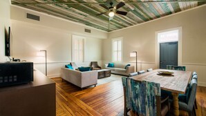 A spacious living room with a wooden floor, a ceiling fan, and a dining area with a wooden table and chairs. - Hotel Florence, Tapestry Collection by Hilton (Florence)
