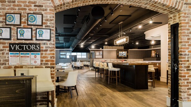 A restaurant with brick walls, framed awards, and a bar area. - Hotel Florence, Tapestry Collection by Hilton (Florence)