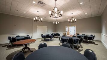A conference room with round tables, chairs, and a wooden table in the center.