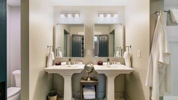 A bathroom with two sinks, a mirror, and a toilet.