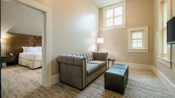 A bedroom with a bed, a gray sofa, a small table, and a TV.