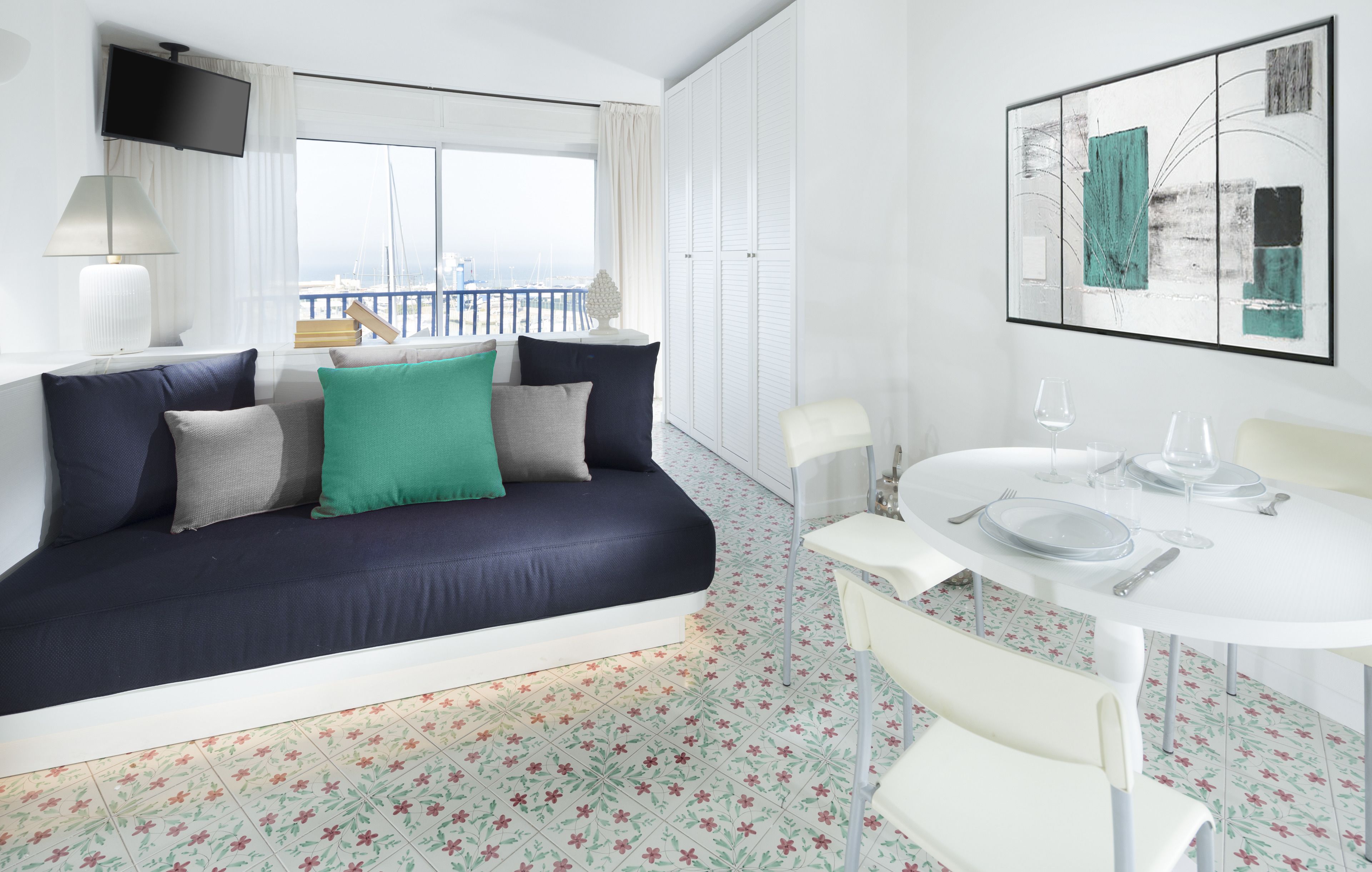 A modern hotel room with a sofa, dining table, and chairs.