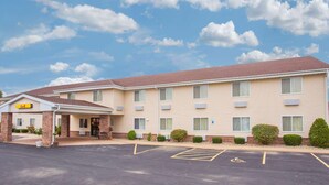 Un motel de dos pisos con techo plano, entrada cubierta y estacionamiento, incluyendo espacios para discapacitados.