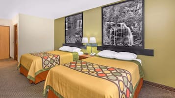 A hotel room with two beds, each with a patterned bedspread, a nightstand with a lamp, and two framed black and white waterfall photographs on the wall.