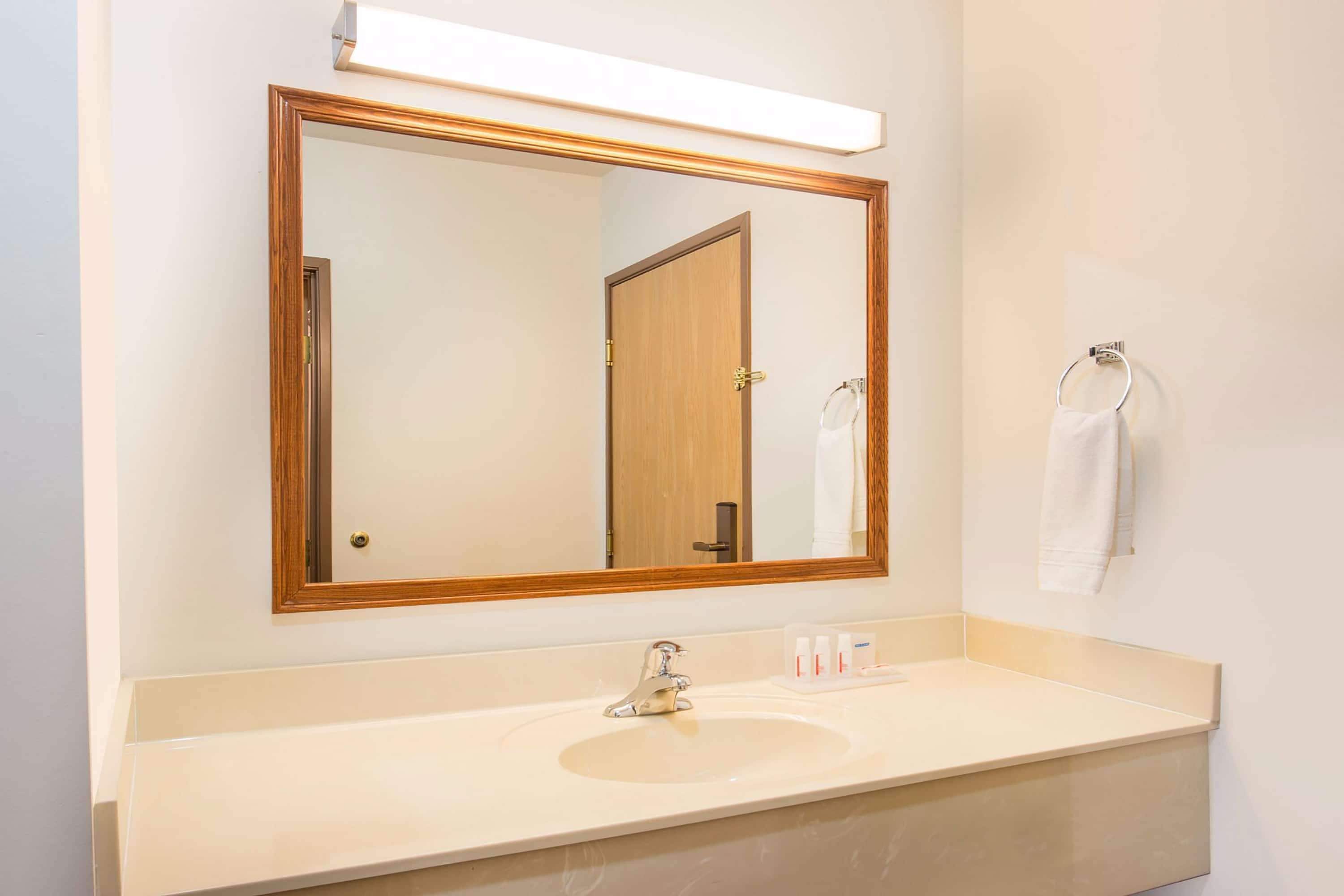 Un baño con un espejo grande, un lavabo y un perchero para toallas.