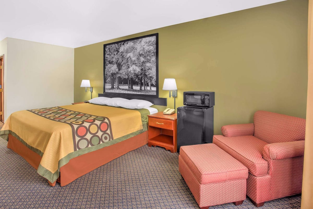 A hotel room with a bed, a television, a chair, and a telephone.