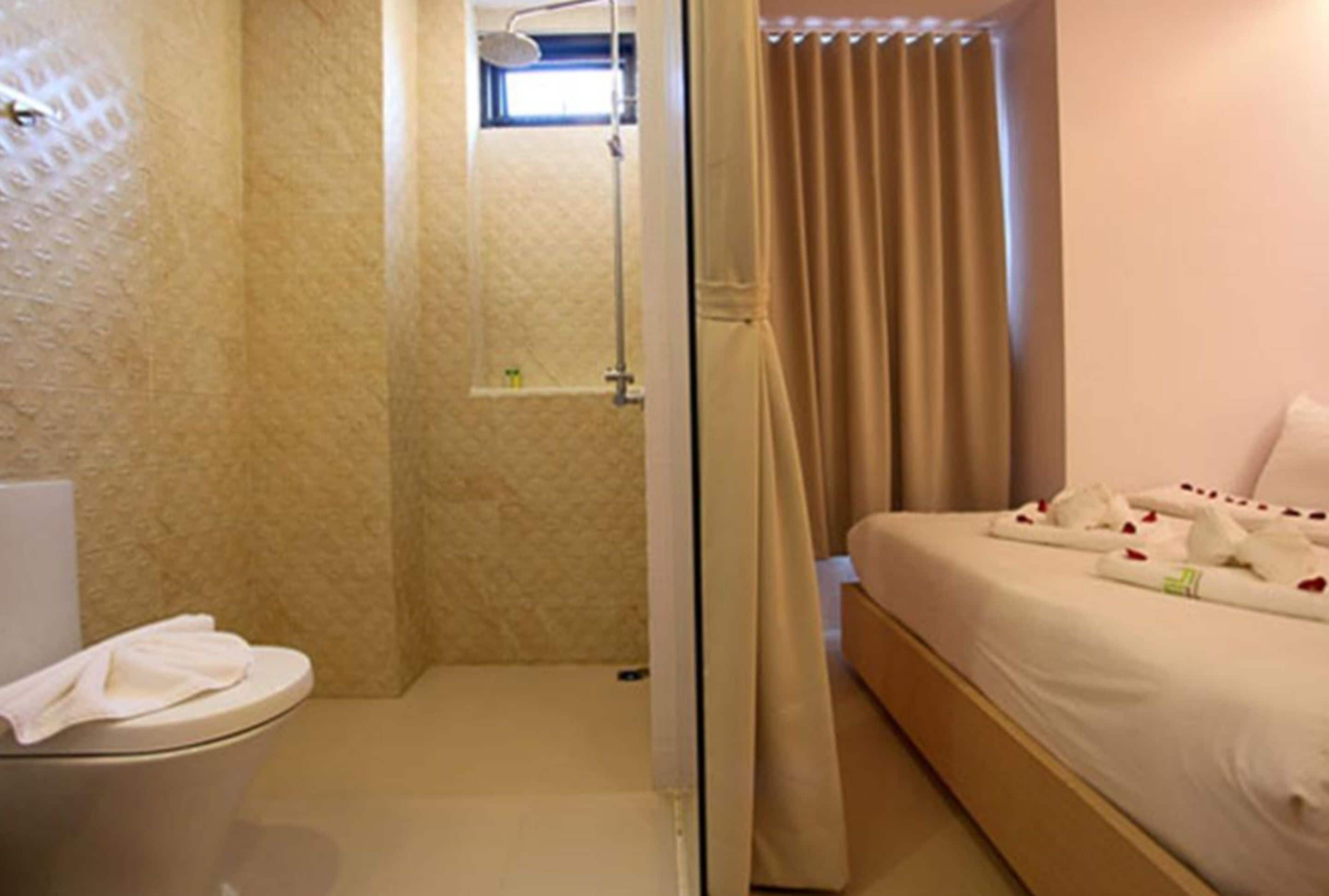 Habitación de hotel con ducha, inodoro y cama.