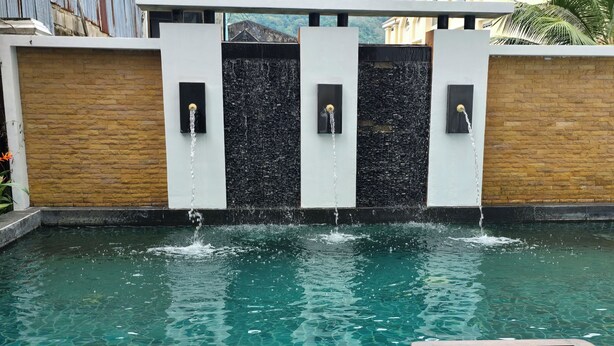 Une piscine agrémentée de jeux d’eau, dotée d’une terrasse en bois et de chaises longues.