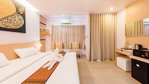 Une chambre d’hôtel équipée d’un lit, d’un bureau, d’un réfrigérateur et d’un miroir.