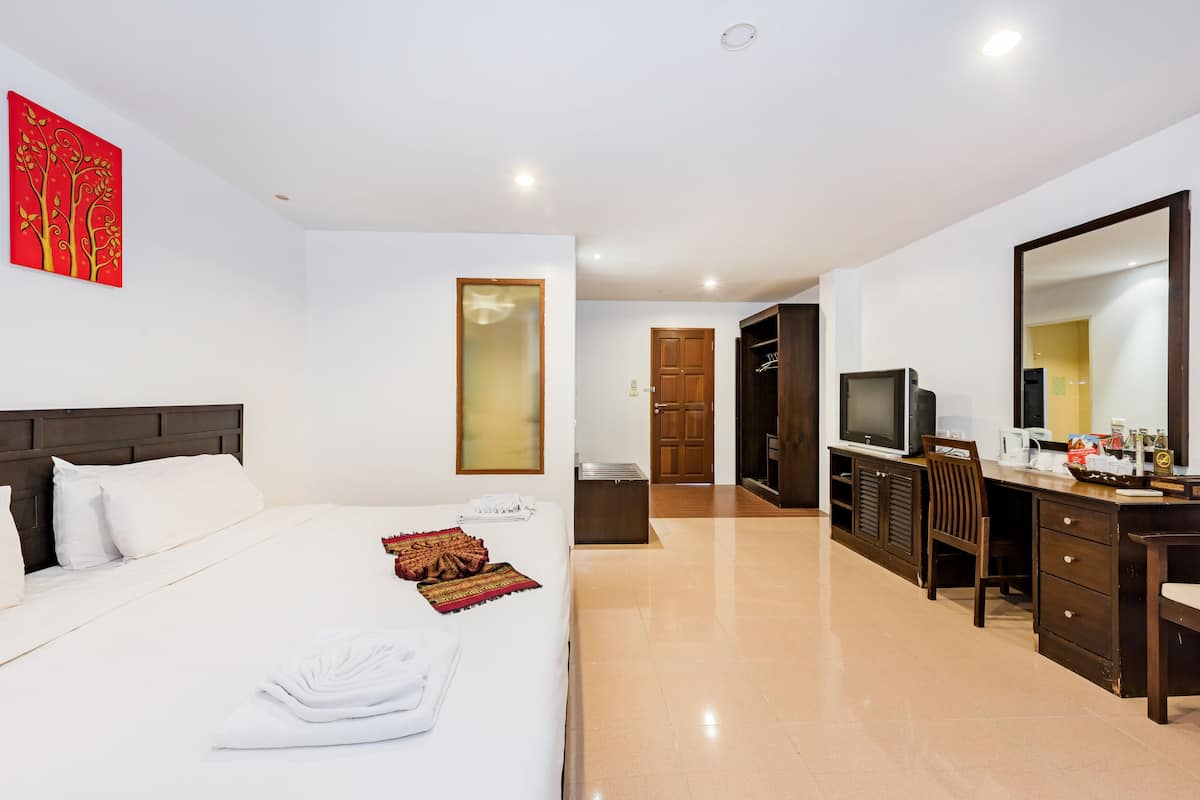 A hotel room with a bed, a desk, a television, and a mirror.