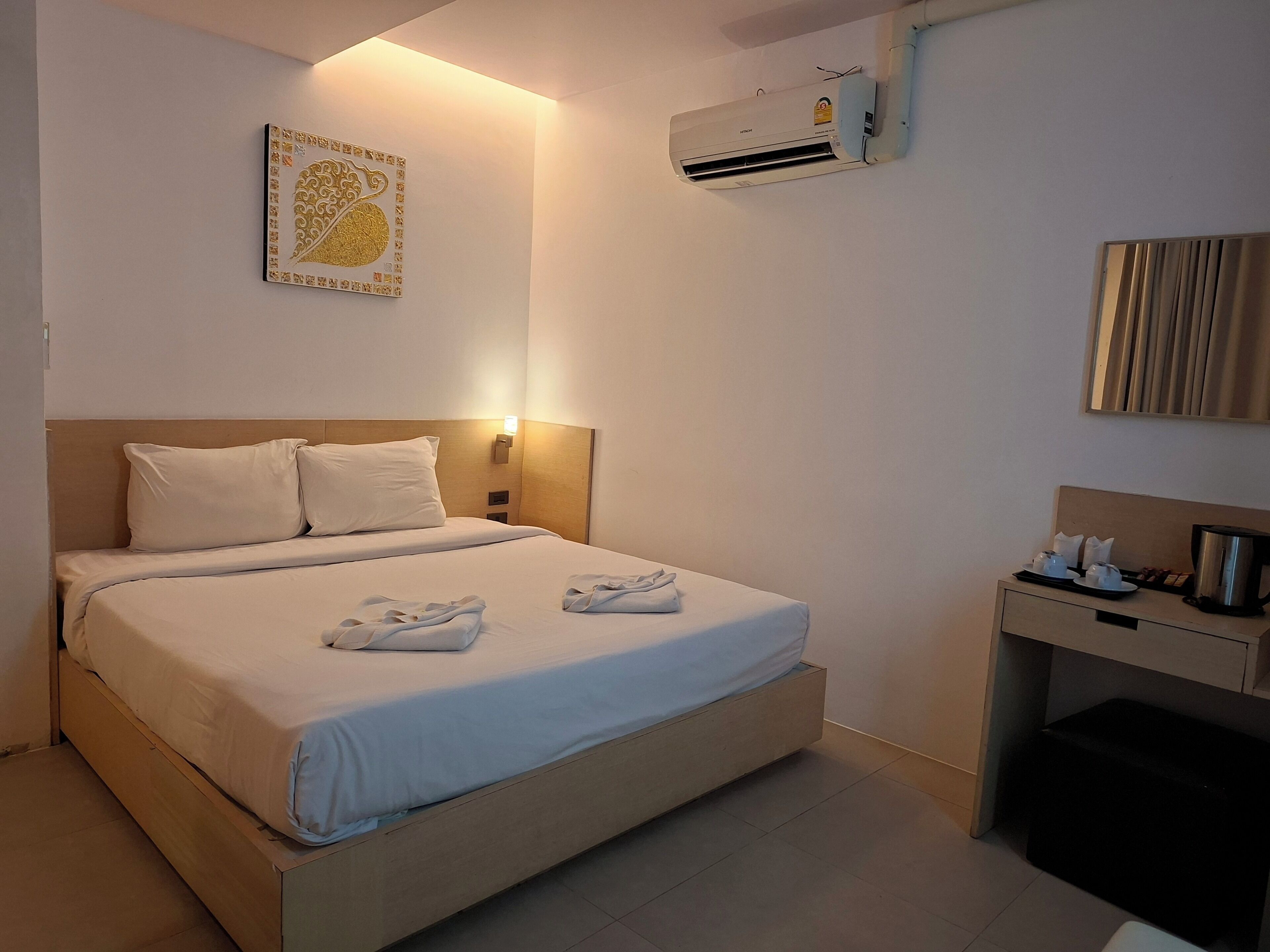 Una habitación de hotel con cama, mesita de noche y un equipo de aire acondicionado.