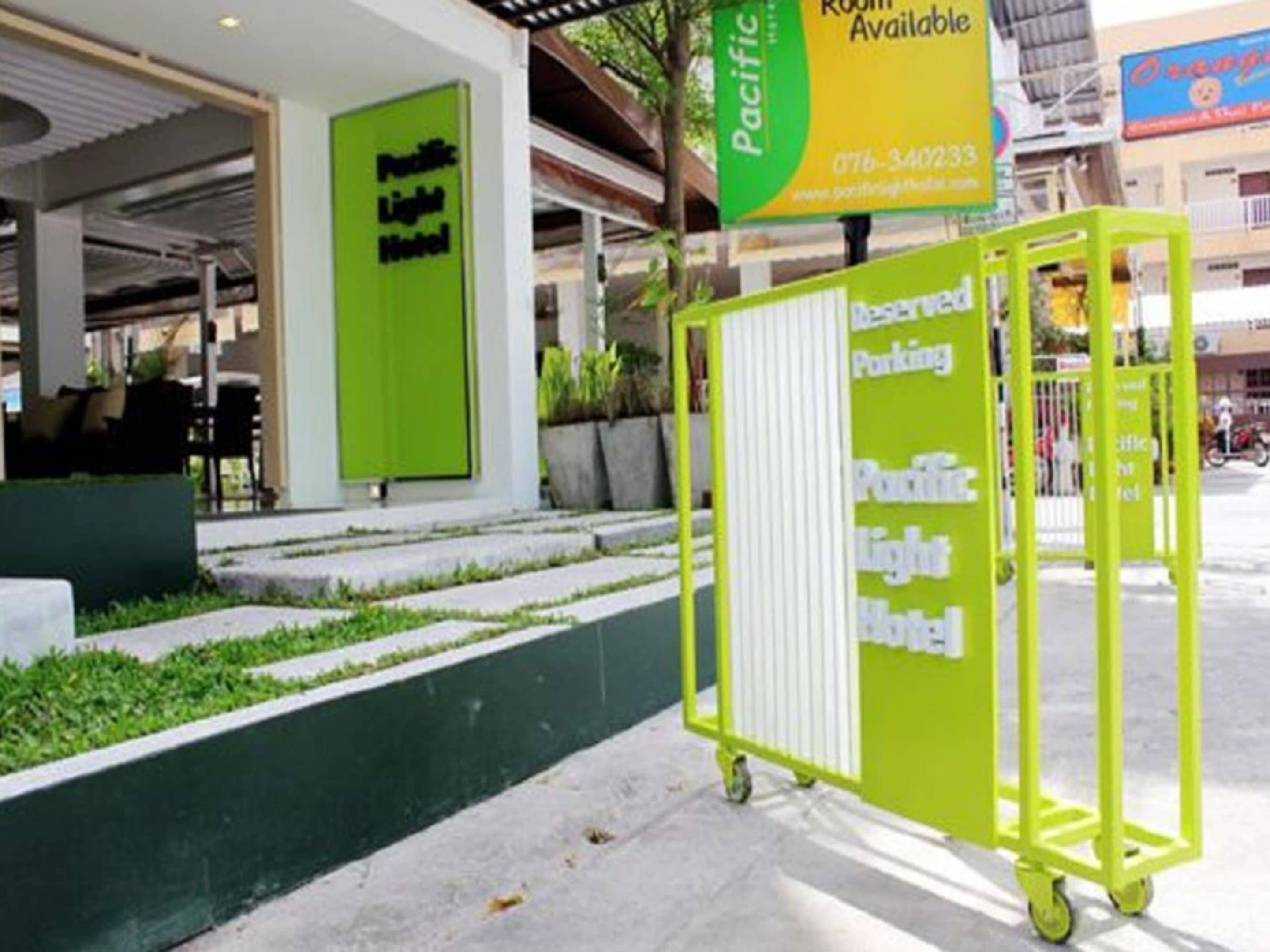 Un hôtel ouvert au public, reconnaissable à son panneau vert, doté d’un espace de stationnement réservé et d’une entrée bien visible.