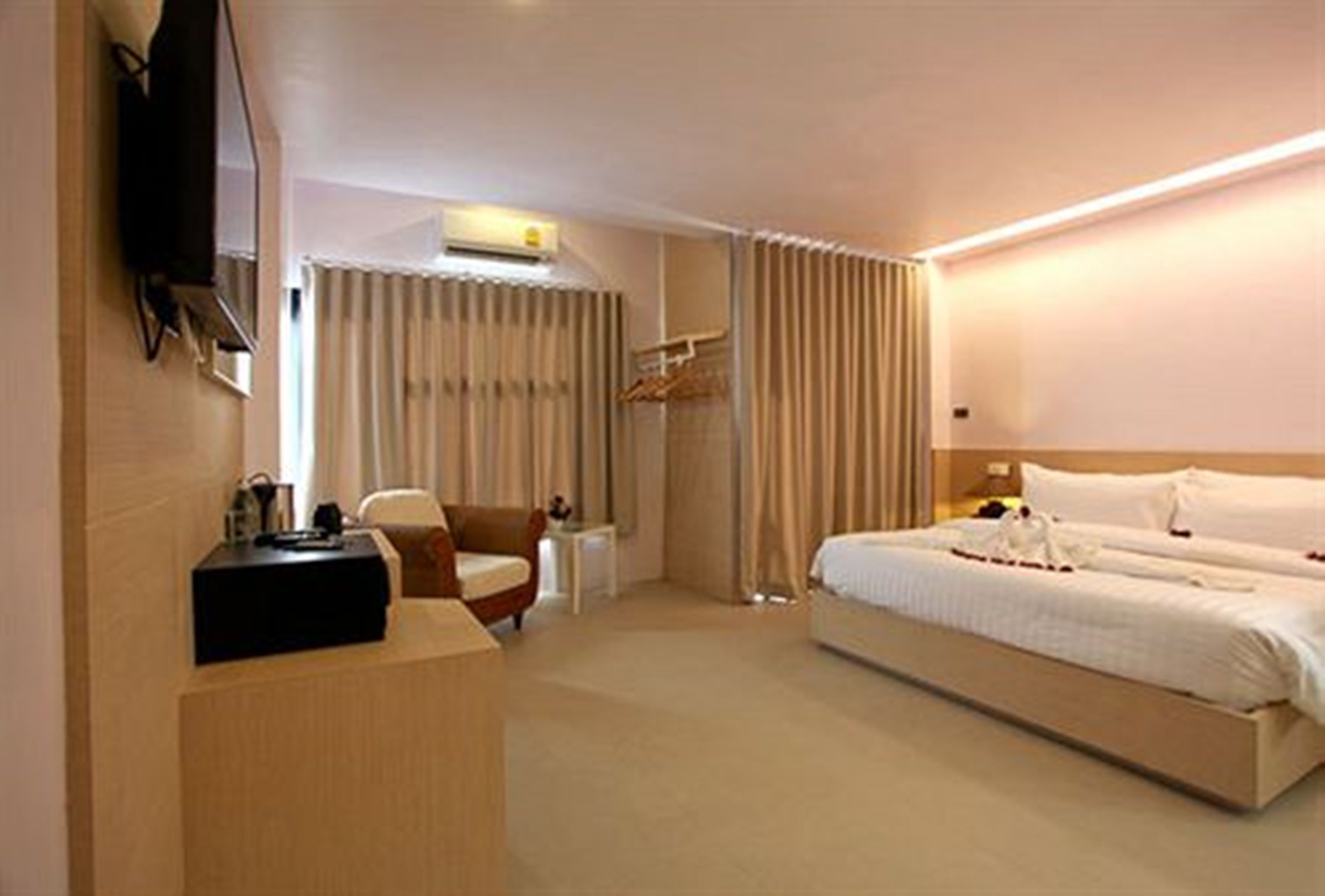 A hotel room with a bed, a desk, a chair, a TV, and a wardrobe.